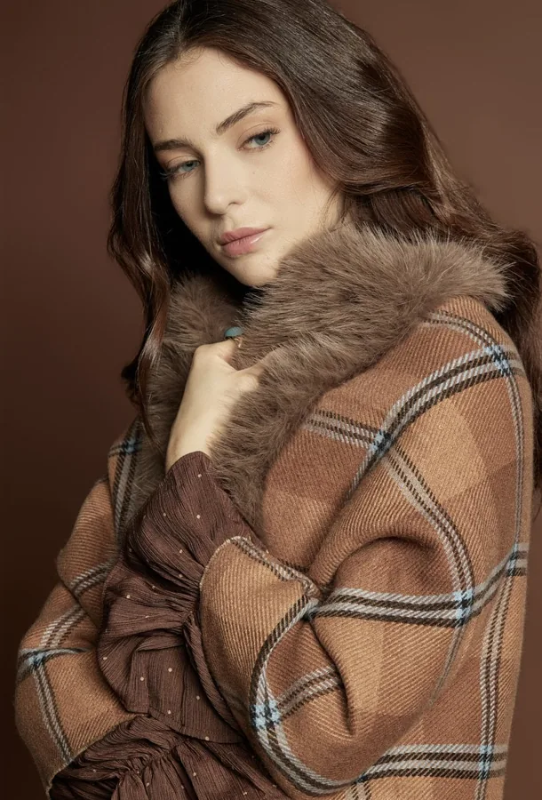 Szalik MONNARI w kratę owinięty wokół ramion modelki.