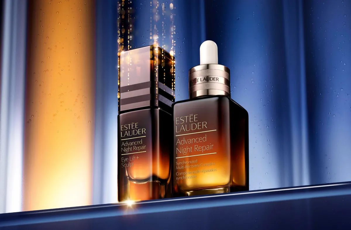 Dwie butelki kosmetyków Estée Lauder Advanced Night Repair na tle złotego i granatowego światła.
