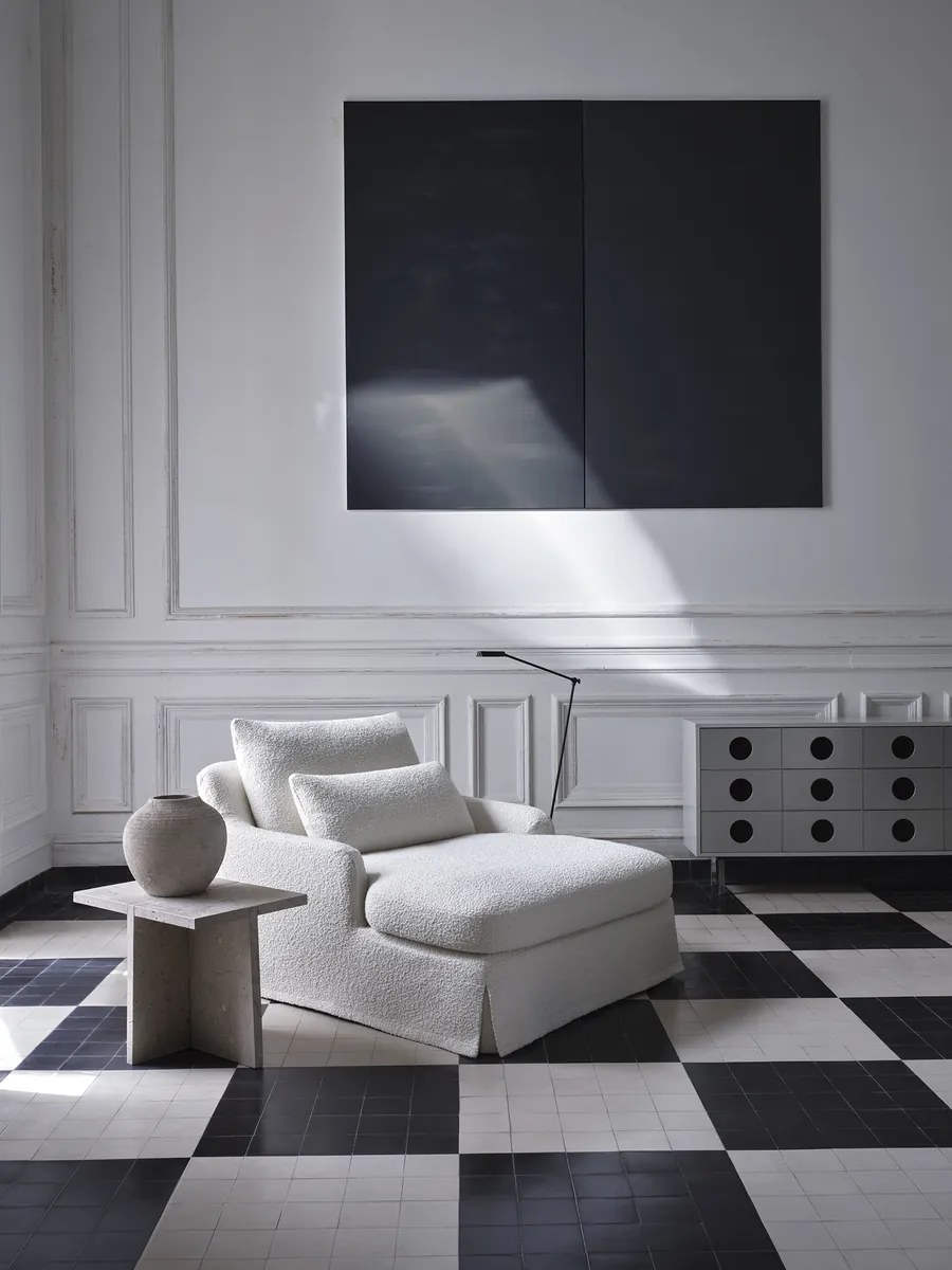 Jasny fotel i kamienny stolik w salonie z czarno-białą posadzką, kolekcja Zara Home by Vincent Van Duysen